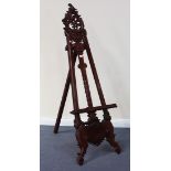 A 20th Century reproduction carved hardwood artist's easel with pierced and scrolling decoration,