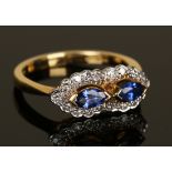 An 18ct gold, sapphire and diamond ring, mounted with two marquise shaped sapphires in a surround of