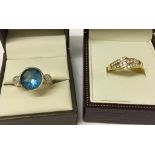 2 gold plated silver rings. One with large central blue stone size R, the other with 3 rows of white