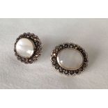 A pair of 925 silver earrings set with oval mother or pearl and surrounded by marcasite stones.