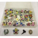 A sectioned box containing more than 20 china flower brooches and earrings all in different