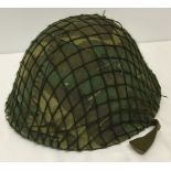 A British Army helmet with liner, camoflage cover and net. Liner bears date for 1981.