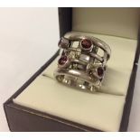 Unusual silver ring with cage design set with 4 garnets. Size P.