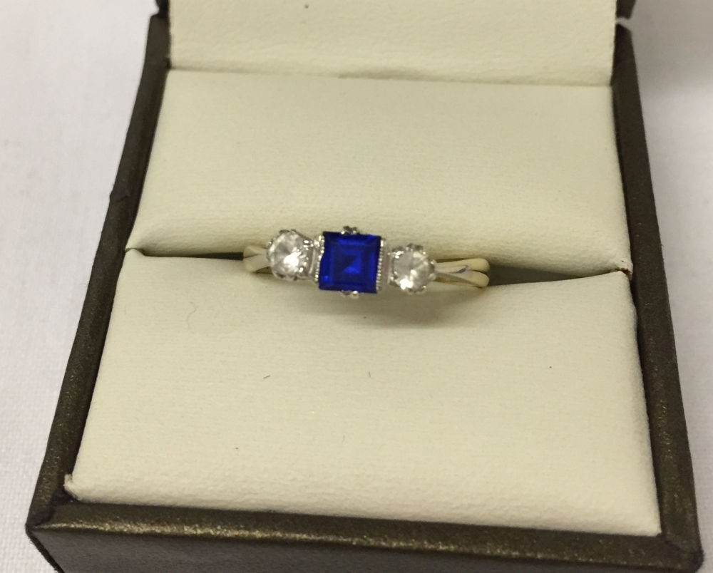 Ladies 9ct gold dress trilogy ring with central square cut blue stone with white stones either side.