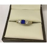 Ladies 9ct gold dress trilogy ring with central square cut blue stone with white stones either side.