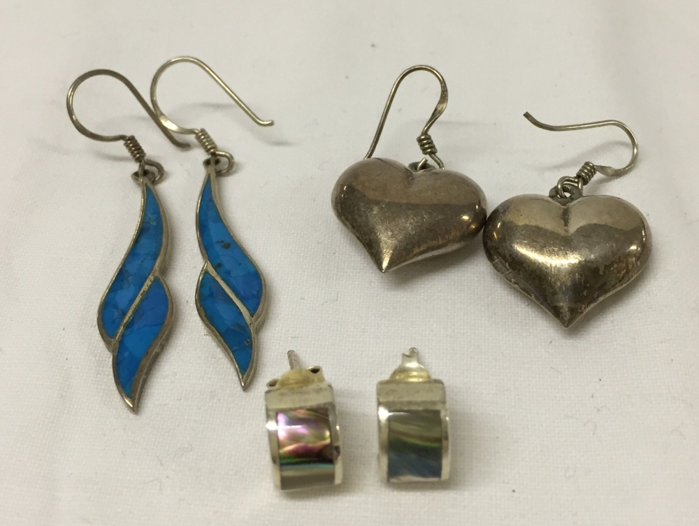 3 pairs of silver earrings. One with hearts, one with abalone shell decoration and one with blue