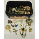 A tub containing costume jewellery rings and brooches.