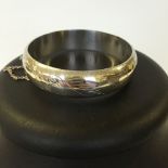 Hallmarked silver hinged bangle with contemporary style engraving and safety chain. Depth approx 1.