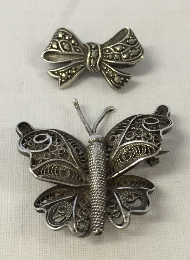 2 pretty brooches, 1 in the shape of a butterfly with filligree work and the other a bow set with