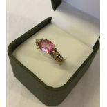 Ladies dress ring set with a large oval pink topaz in an ornate open mount studded with 6 small