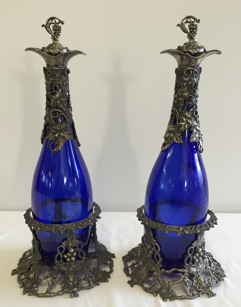 A pair of blue glass decanters in metal coasters, 36cm tall