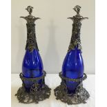 A pair of blue glass decanters in metal coasters, 36cm tall