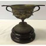 A heavy early 20th century/late 19th century brass cup on ceramic base.