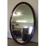 An Edwardian oval mirror with inlaid banding.