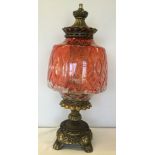 A large gilt metal table lamp with red painted glass shade.
