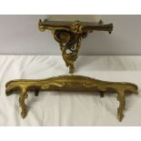 A gold painted decorative wall bracket together with a small painted shelf.