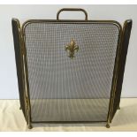 A brass fire guard with fleur de lis decoration.