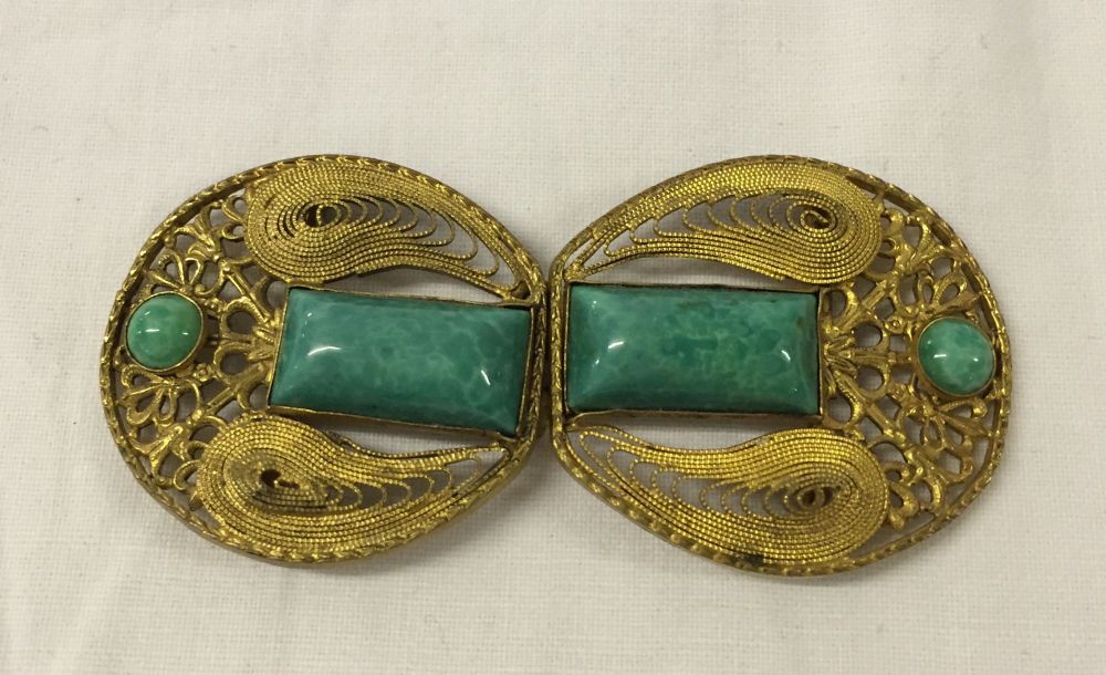 A vintage figure belt buckle set with turquoise.