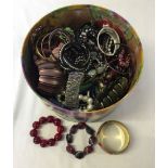 A round box containing a large quantity of costume jewellery bangles and bracelets.