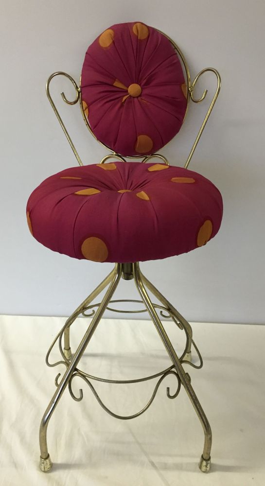 A boudoir chair with orange spotted pink upholstery.