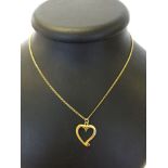 A 9ct gold hallmarked open heart pendant set with a small ruby. On a 9ct gold chain. Weight approx