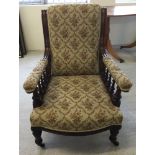 A Victorian armchair with rail sides, china casters and gold upholstery.