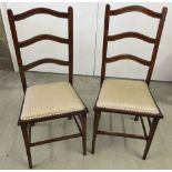 A pair of Edwardian ladder back chairs with inlaid banding and gold striped upholstery.