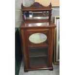 An early 20th century mahogany cabinet with display shelf, oval mirror to door and mirror & shelf to