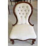 A Victorian mahogany framed button back nursing chair upholstered in cream fabric.