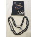 A boxed 48 inch haematite necklace with a Guide to Gems & Jewellery book.