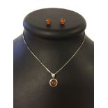 A faux amber pendant on a silver 15" box chain with matching faux amber stud earrings.