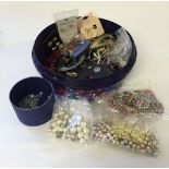 A round box containing costume jewellery, some still on cards, together with beads suitable for