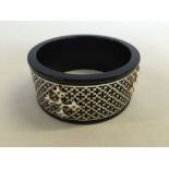 A black resin bangle with silver fretwork cladding set with white topaz stones.