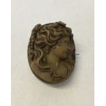 A brooch of a ladies head carved into a brown coloured stone (cameo style) possibly Italian marble.