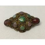 Ornate brooch set with semi-precious stones to include jade, amethyst, adventurine, larrimar, rose