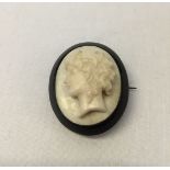A brooch of a ladies head carved into a white coloured stone set in jet (possibly italian marble).