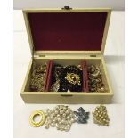 A cream jewellery box containing a quantity of costume jewellery