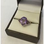 A 9ct gold dress ring set with a large pear cut amethyst and amethyst set shoulders. Size approx O½,