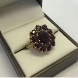 9ct gold & garnet cluster ring, central oval garnet surrounded by 10 circular garnets, size O,