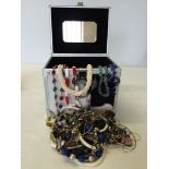 A metal jewellery case with faux fur, containing a large amount of costume jewellery.