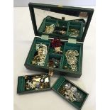 A green jewellery box containing costume jewellery.