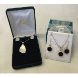 2 sets of silver pendants and earrings. One is set with mother of pearl and the other set with black