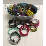 Tinplate tub containing a large quantity of costume necklaces and bangles.