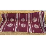 Maroon and white woven rug with tassels, 162cm x 89cm.