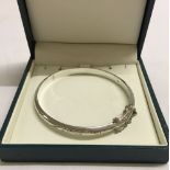 A 925 hinged, engraved bangle with safety chain. Approx weight 6.8g.