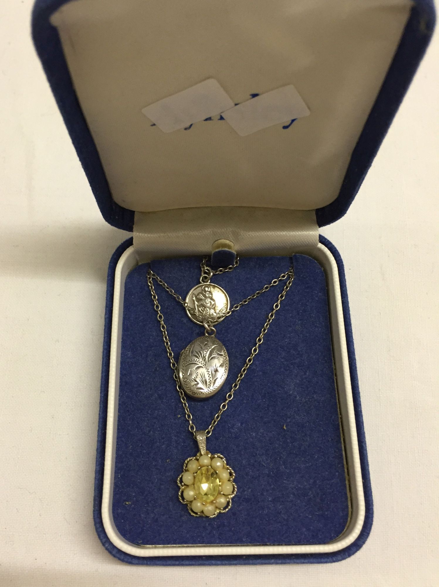 3 silver pendants & chains comprising of an oval engraved locket 1.75cm long, a St Christohpers