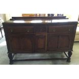 A dark oak sideboard with carved legs and decorative panels to front.