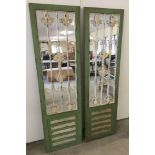 A pair of green and white painted mirror panels in wooden mounts with metal decoration.