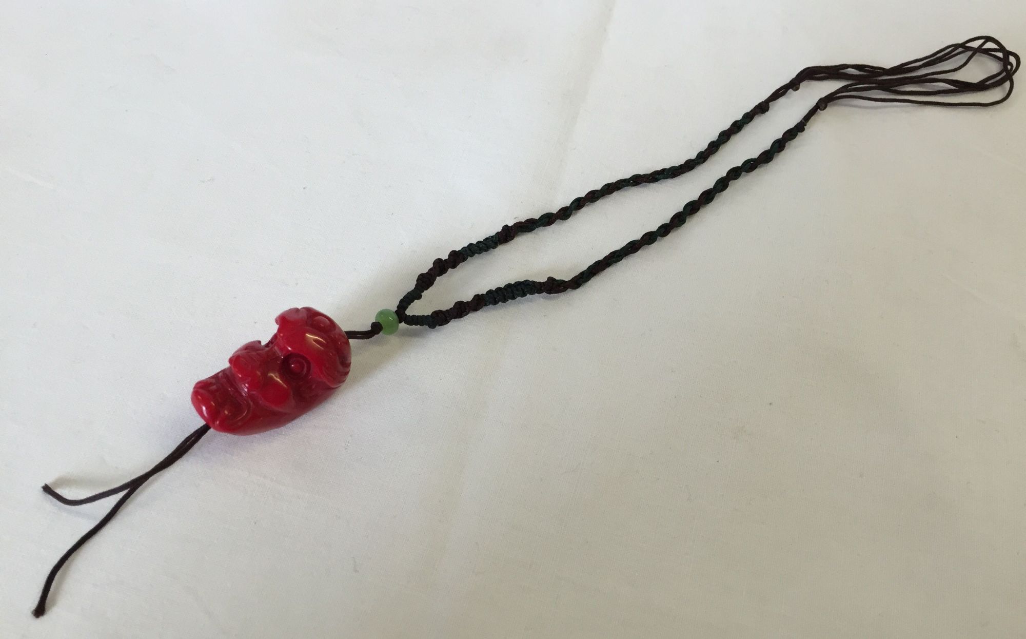 A braided thong necklace with a carved coral skull bead.