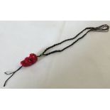 A braided thong necklace with a carved coral skull bead.